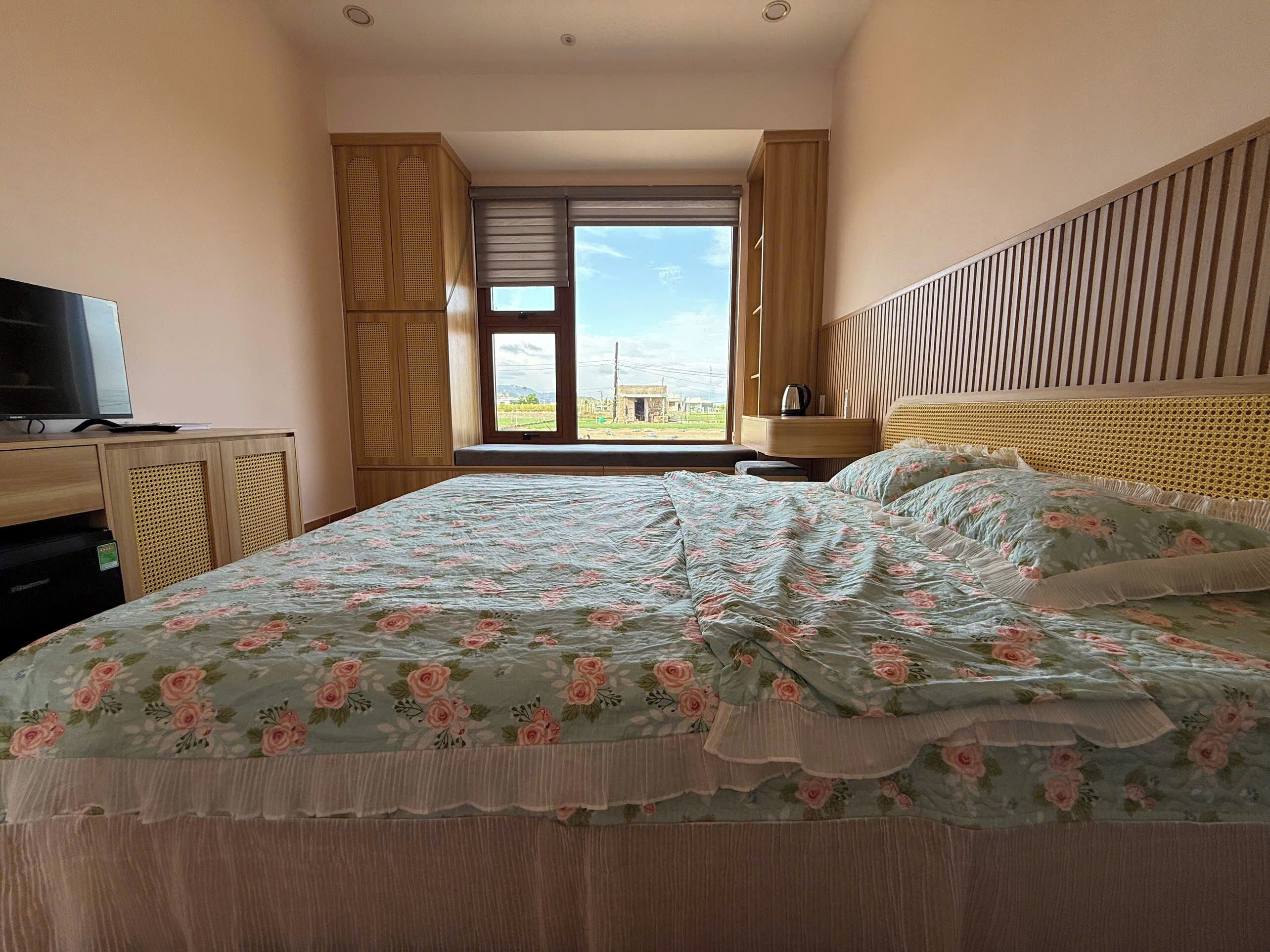 Une chambre à coucher avec un lit, une télévision, une fenêtre donnant sur un beau paysage et une armoire en bois.
