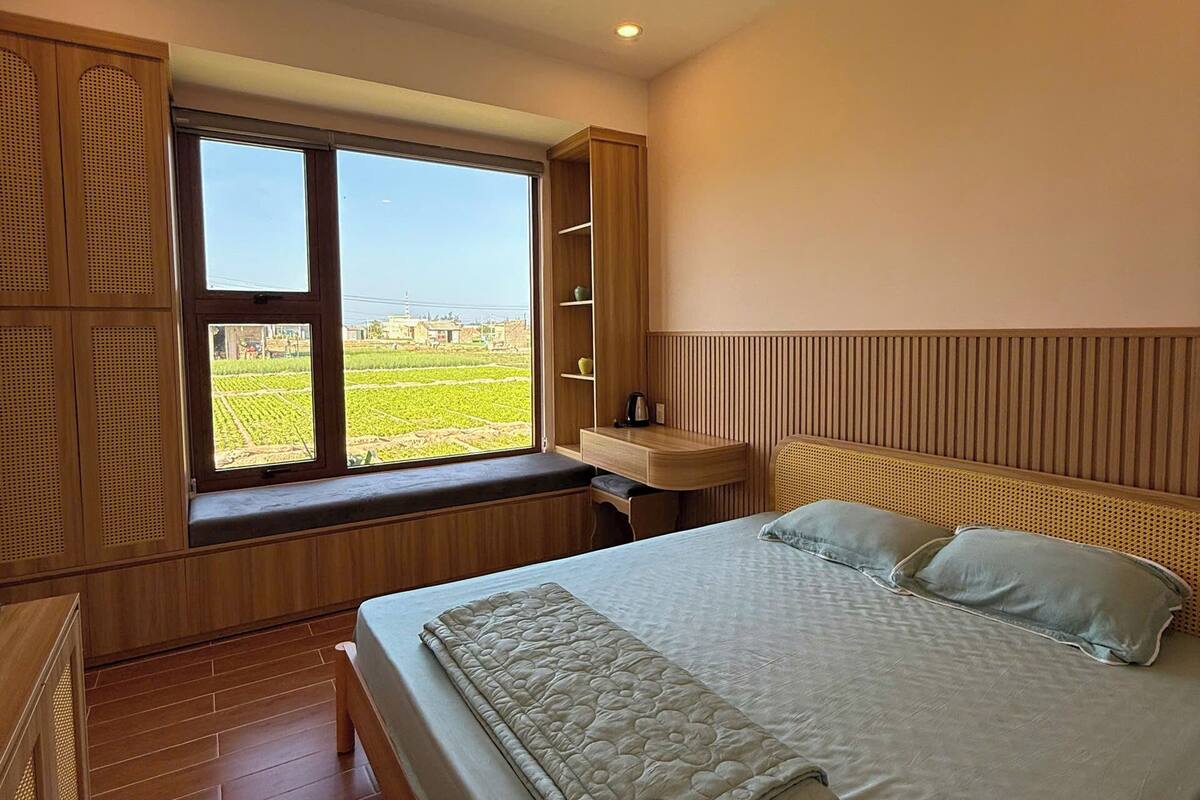 Un dormitorio con un ventanal grande, muebles de madera y una cama con almohadas.