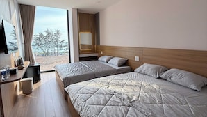 A hotel room with two beds, a desk with a TV, a mirror, and a view of the outdoors.