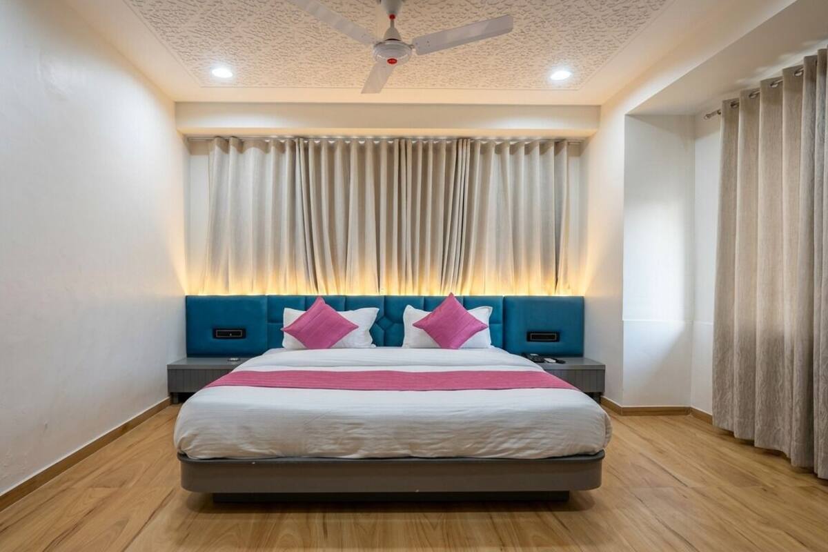 Um quarto moderno com uma cama, mesas de cabeceira, um ventilador de teto e cortinas.