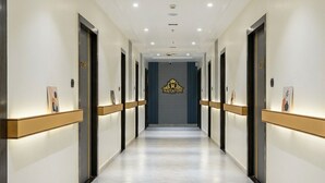 A hotel hallway with a central logo, doors numbered 208 and 231, and framed pictures on the walls. - Hotel Rajvanshi Inn (Ahmedabad)