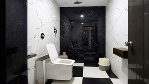 A modern bathroom with a toilet, bidet, and a black and white checkered floor. - Hotel Rajvanshi Inn (Ahmedabad)