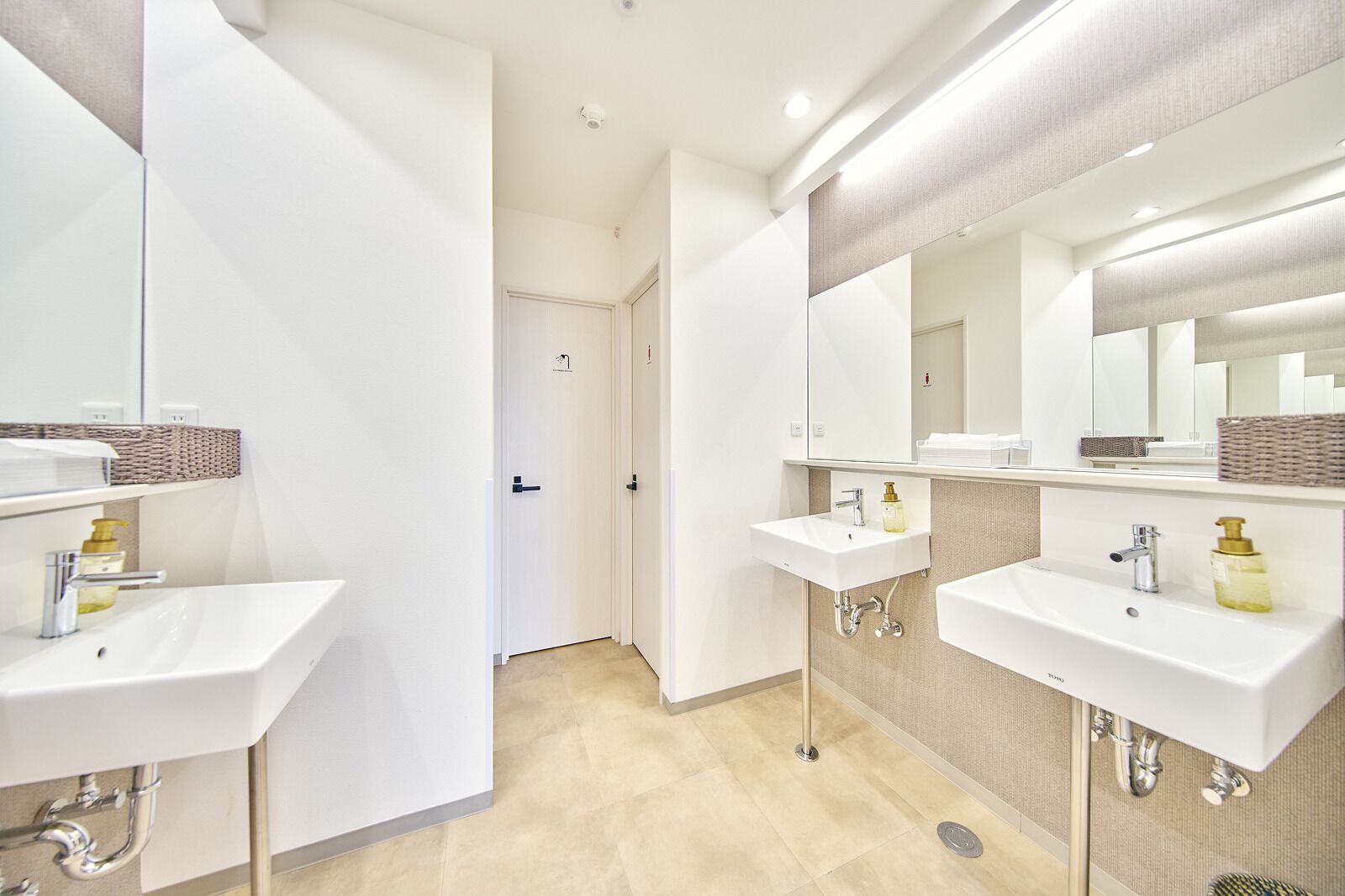 Un bagno moderno con due lavandini, uno specchio e una porta che dà su un'altra stanza.