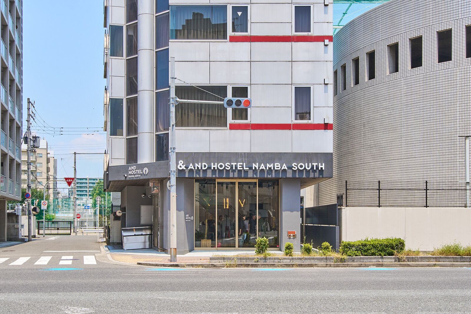Un edificio moderno con un cartel que indica 'And Hostel Namba South', señalando un alojamiento tipo hostal.