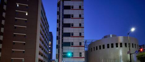 Un hotel de diseño moderno, con una estructura vertical destacada y un edificio cilíndrico de fachada metálica.