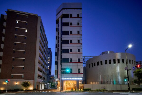 A hotel with a modern design, featuring a prominent vertical structure and a cylindrical building with a metallic facade.