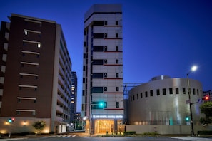 Un hotel de diseño moderno, con una estructura vertical destacada y un edificio cilíndrico de fachada metálica.