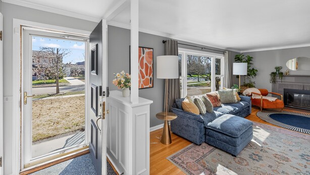 A living room with a blue sofa, a fireplace, and a view of the outside. - Irish Safari Retreat / Walk to Zoo / Minutes to Notre Dame (South Bend)