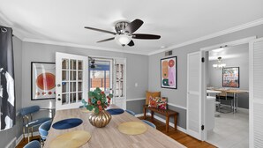 A dining area with a wooden table, blue chairs, a ceiling fan, and a view through a door. - Irish Safari Retreat / Walk to Zoo / Minutes to Notre Dame (South Bend)