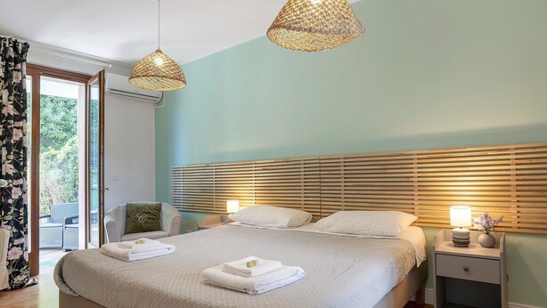 Ein Schlafzimmer mit einem Bett, Nachttischen, einem Sessel und einem Fenster.