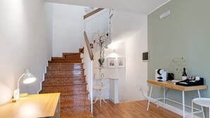Eine Treppe führt zu einer Zwischenebene mit einem Schreibtisch, einem Stuhl und einem kleinen Tisch mit einer Lampe.
