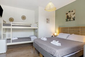 Una stanza con un letto a castello, un letto singolo, una scrivania e una lampada.