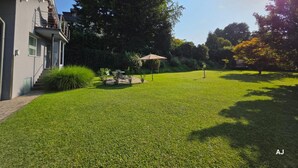 Il s’agit d’une propriété résidentielle dotée d’une pelouse bien entretenue, d’une terrasse avec mobilier d’extérieur et d’un grand arbre qui offre de l’ombre.