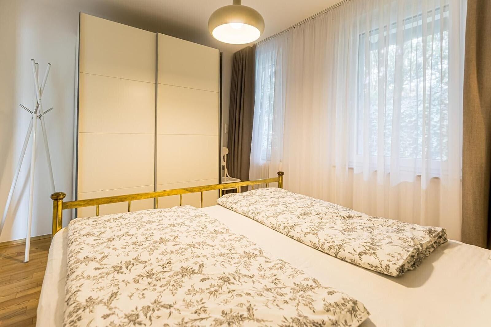Una camera da letto con un letto, un armadio, uno specchio e una finestra con tende.