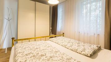 Una camera da letto con un letto, un armadio, uno specchio e una finestra con tende.