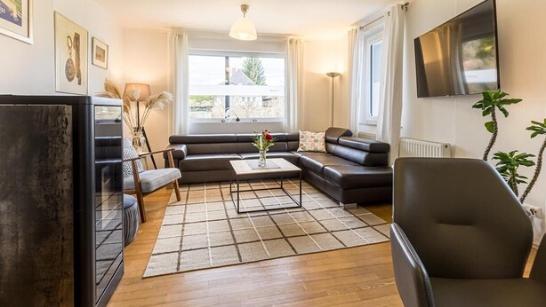 Un salon moderne comprenant un canapé, une table basse, un téléviseur et une grande fenêtre.