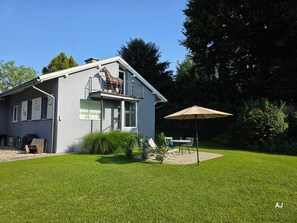 Una casa con balcón, un patio con mesa y sillas, y una estatua de caballo.