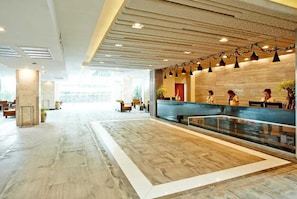 A spacious lobby with a reception desk, seating area, and a large window providing natural light. - Palette Jomtien Beach Pattaya (Pattaya)