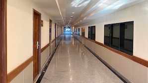 A long, well-lit hallway with doors on one side and windows on the other, leading to a distant area. - Palette Jomtien Beach Pattaya (Pattaya)