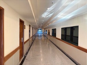 A long, well-lit hallway with doors on one side and windows on the other, leading to a distant area. - Palette Jomtien Beach Pattaya (Pattaya)