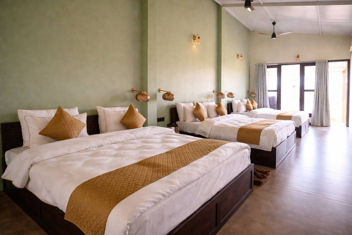 Une chambre d’hôtel avec plusieurs lits, un ventilateur de plafond et une grande fenêtre avec des rideaux.