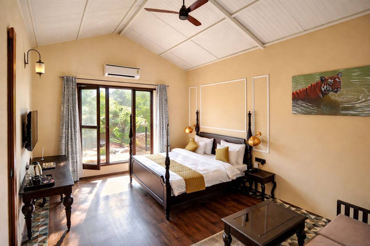 Une chambre à coucher comprenant un lit, des tables de chevet, un téléviseur, un ventilateur de plafond et une grande fenêtre.