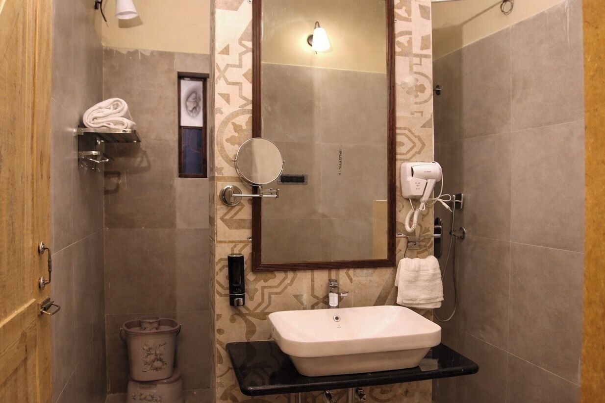 A bathroom with a sink, mirror, towel rack, and a shower area.