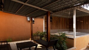Un espace extérieur aménagé en patio, avec un banc en bois, une table et un petit jardin.