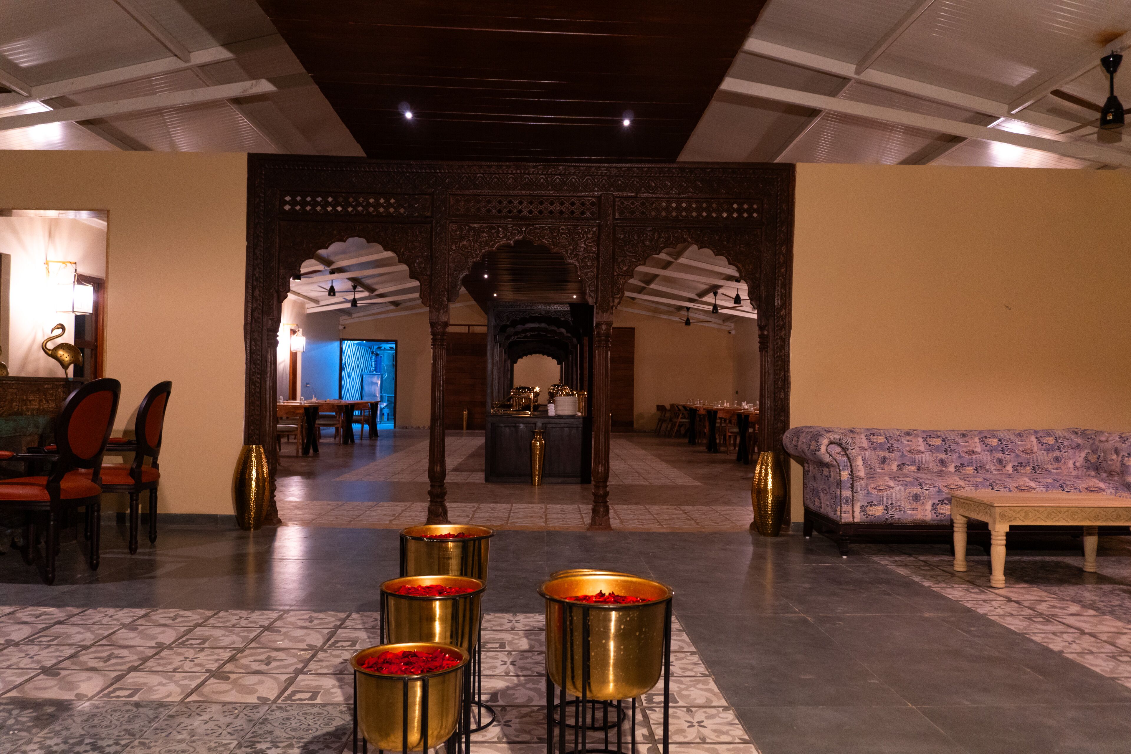 A lobby with a reception desk, a sofa, and a dining area with chairs and tables.