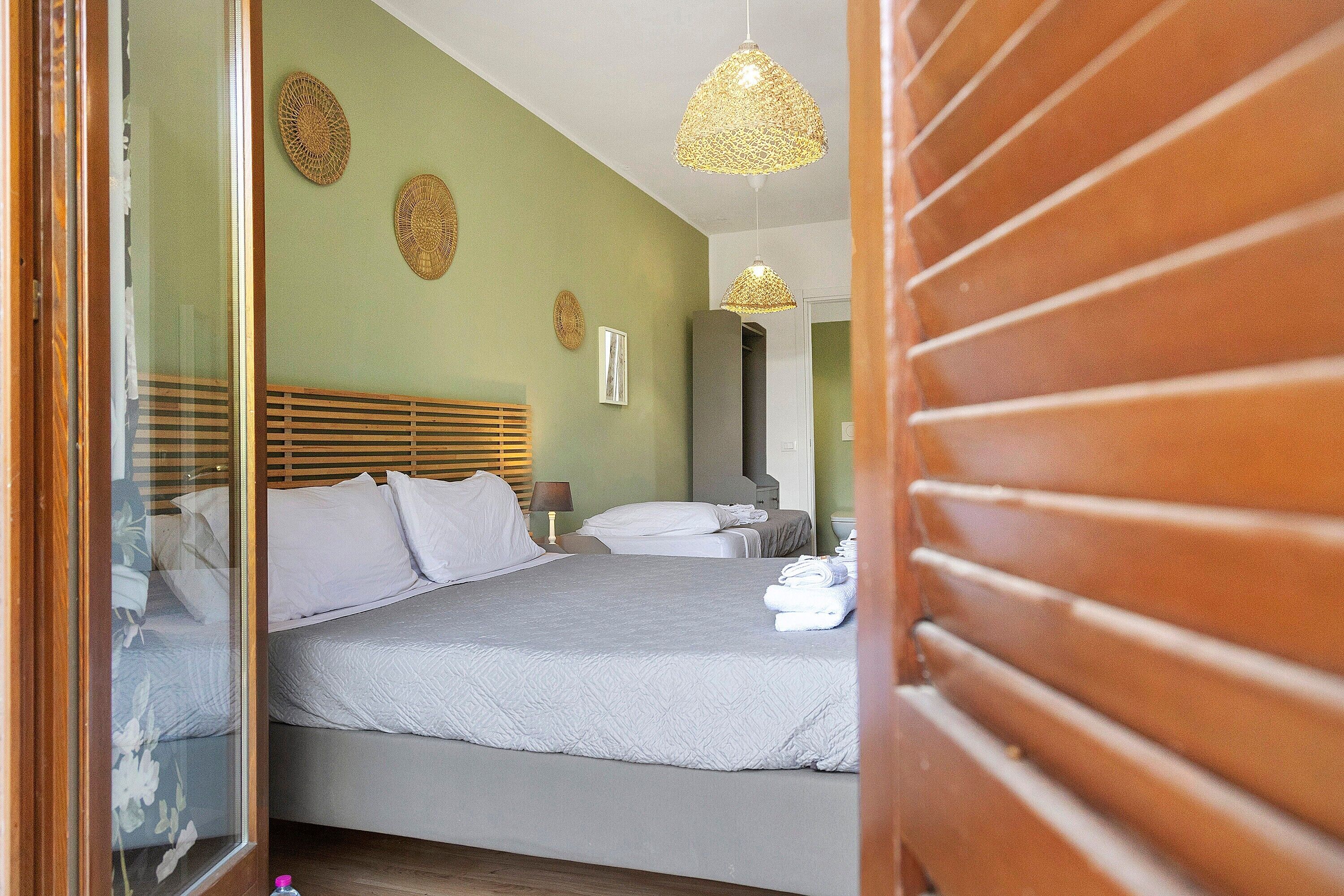 A bedroom with a bed, bedside tables, a mirror, and a hanging light fixture.