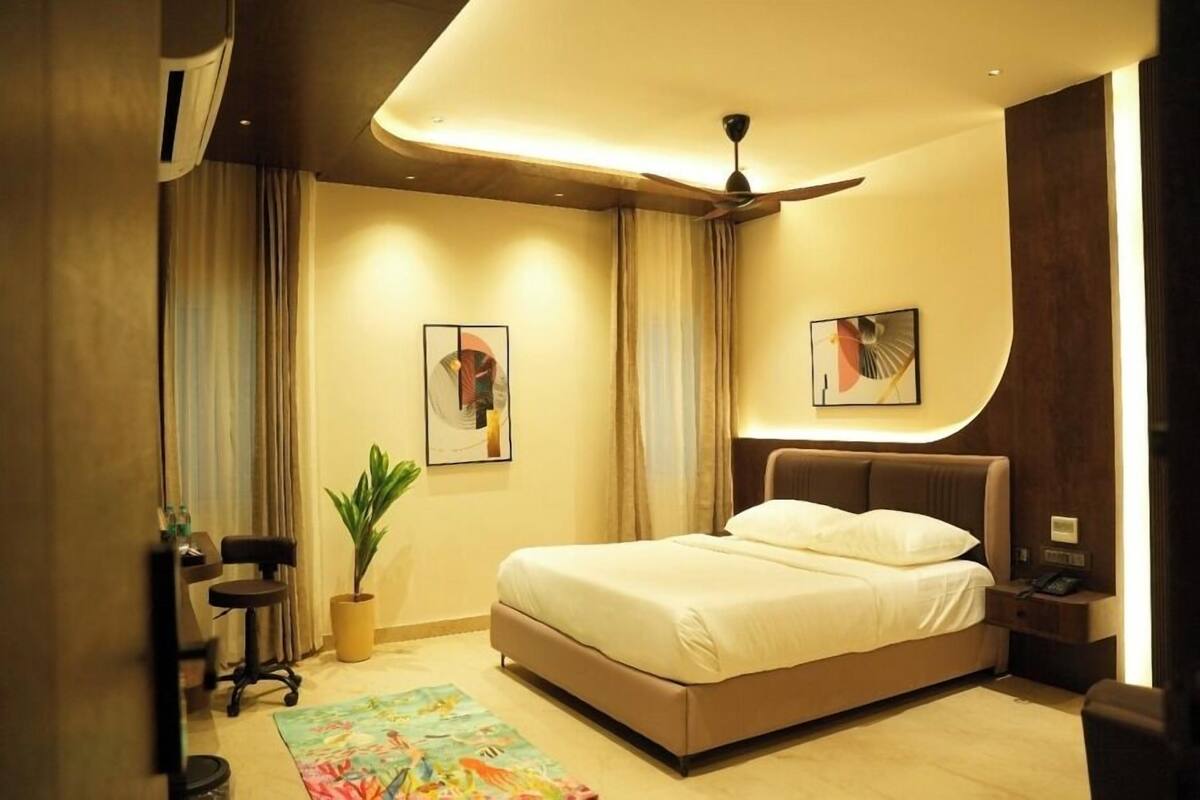Een moderne hotelkamer met een groot bed, een bureau, een stoel, een plant en kunst aan de muren.