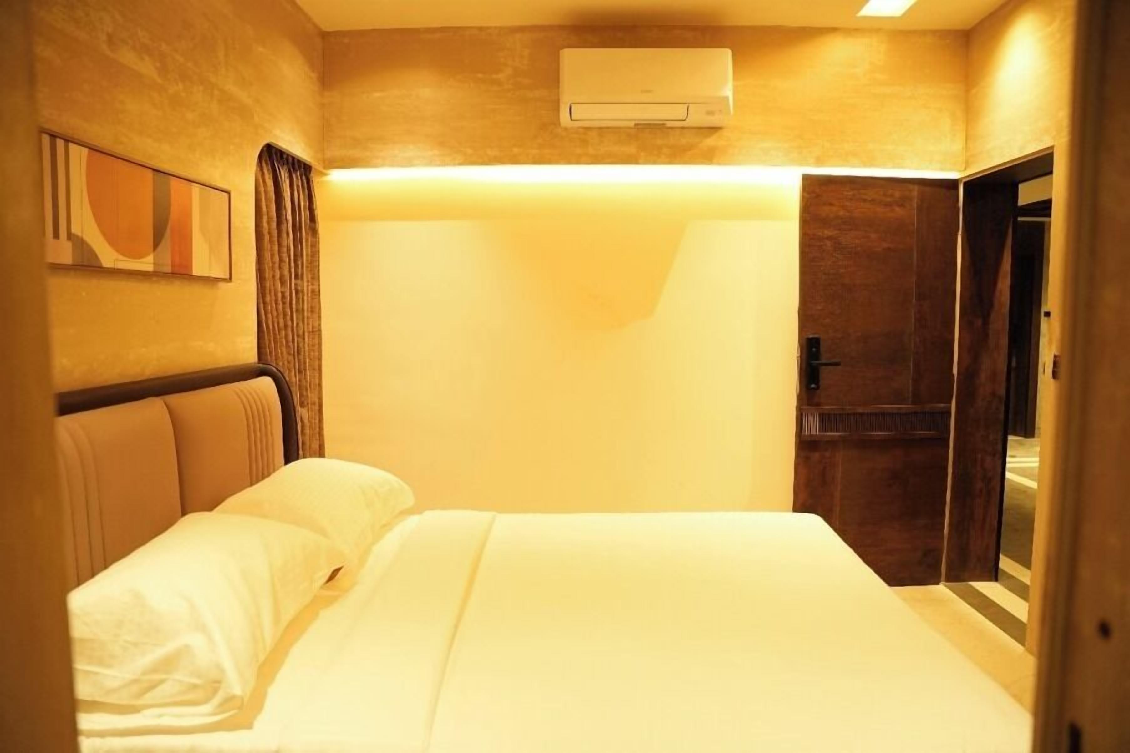 A hotel room with a bed, a wall-mounted air conditioner, and a door.
