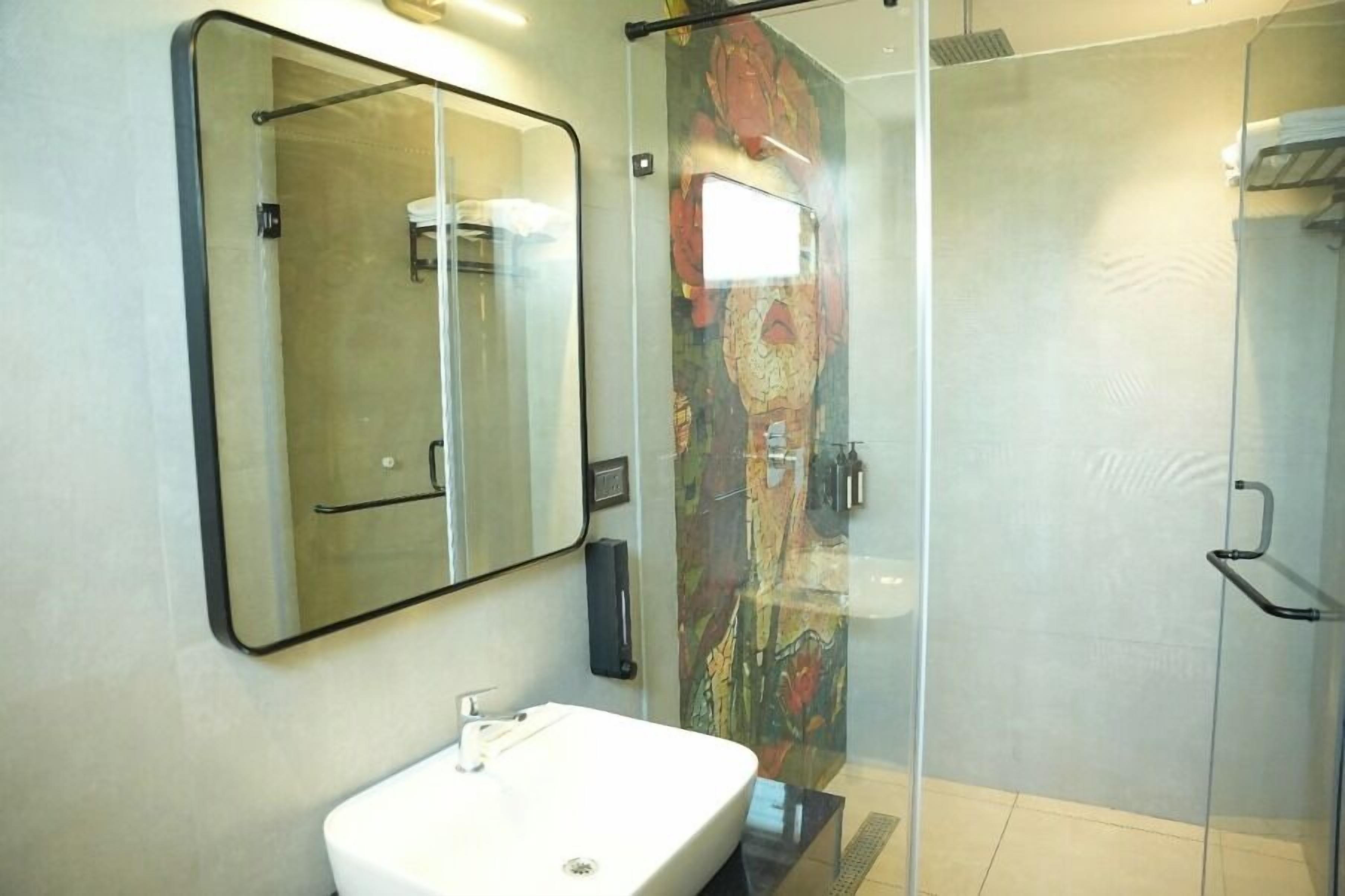 A bathroom with a white sink, a large mirror, and a glass shower enclosure.