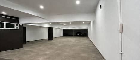 Un espacio interior amplio con suelo de hormigón, paredes blancas y varias luces en el techo.