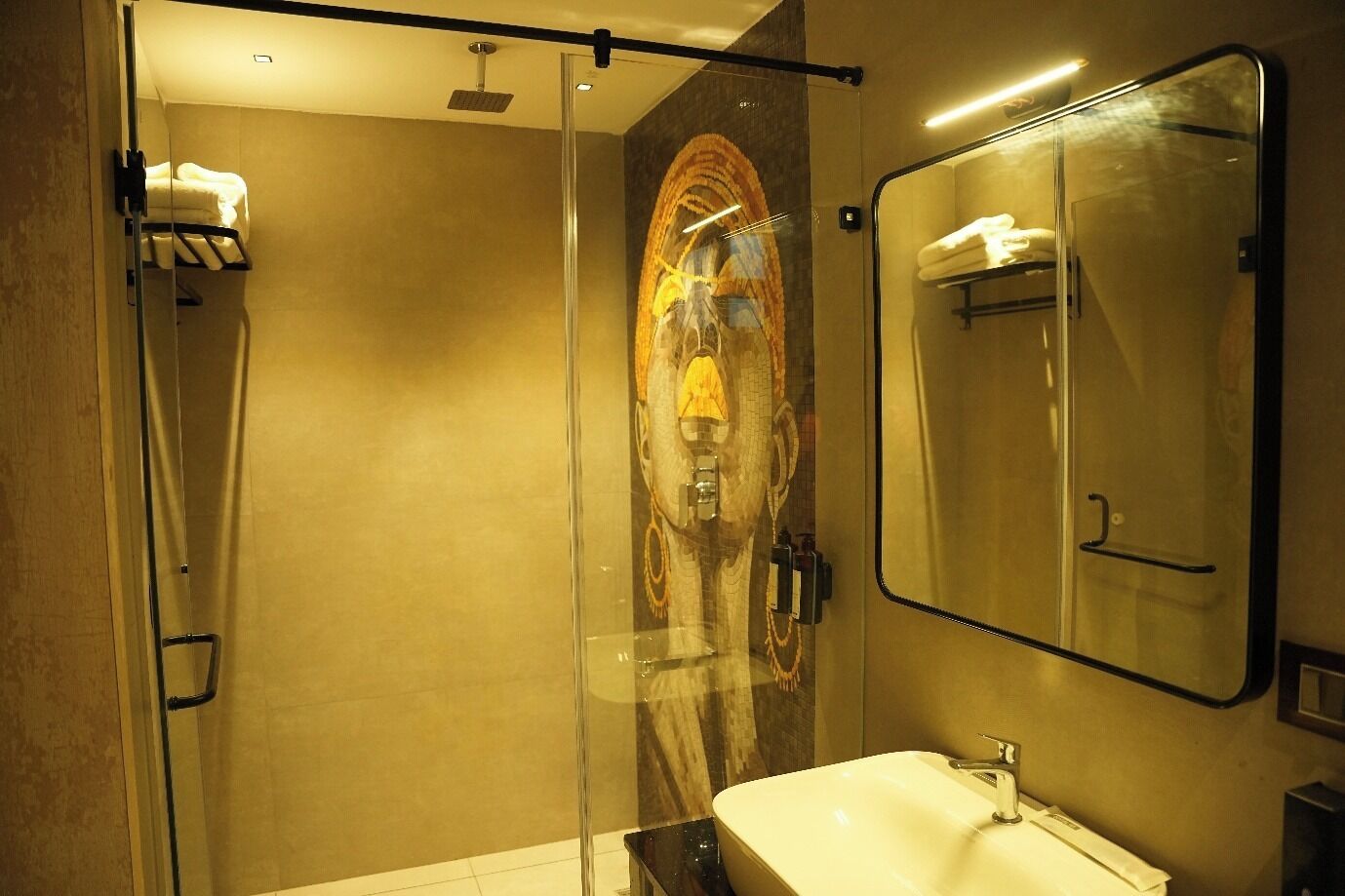A modern bathroom with a glass shower enclosure, a large mirror, and a white sink.