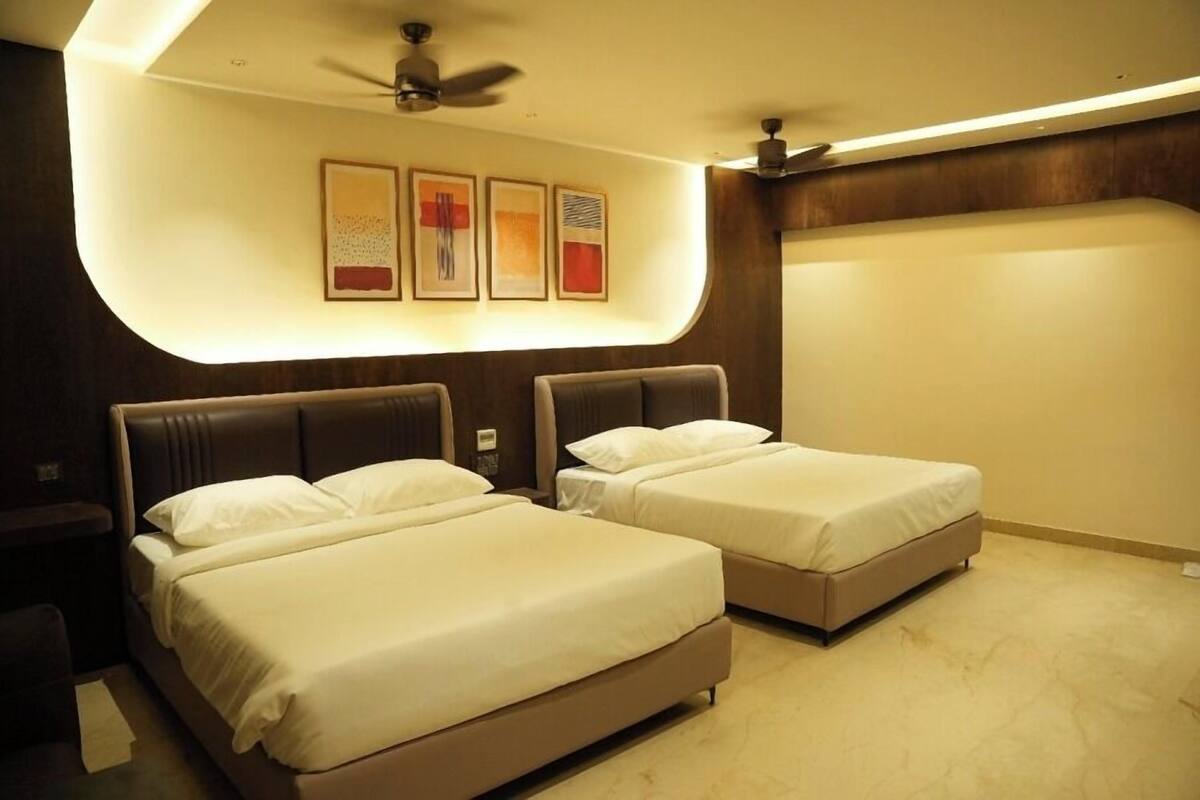 Een hotelkamer met twee bedden, een plafondventilator en kunstwerken aan de muur.