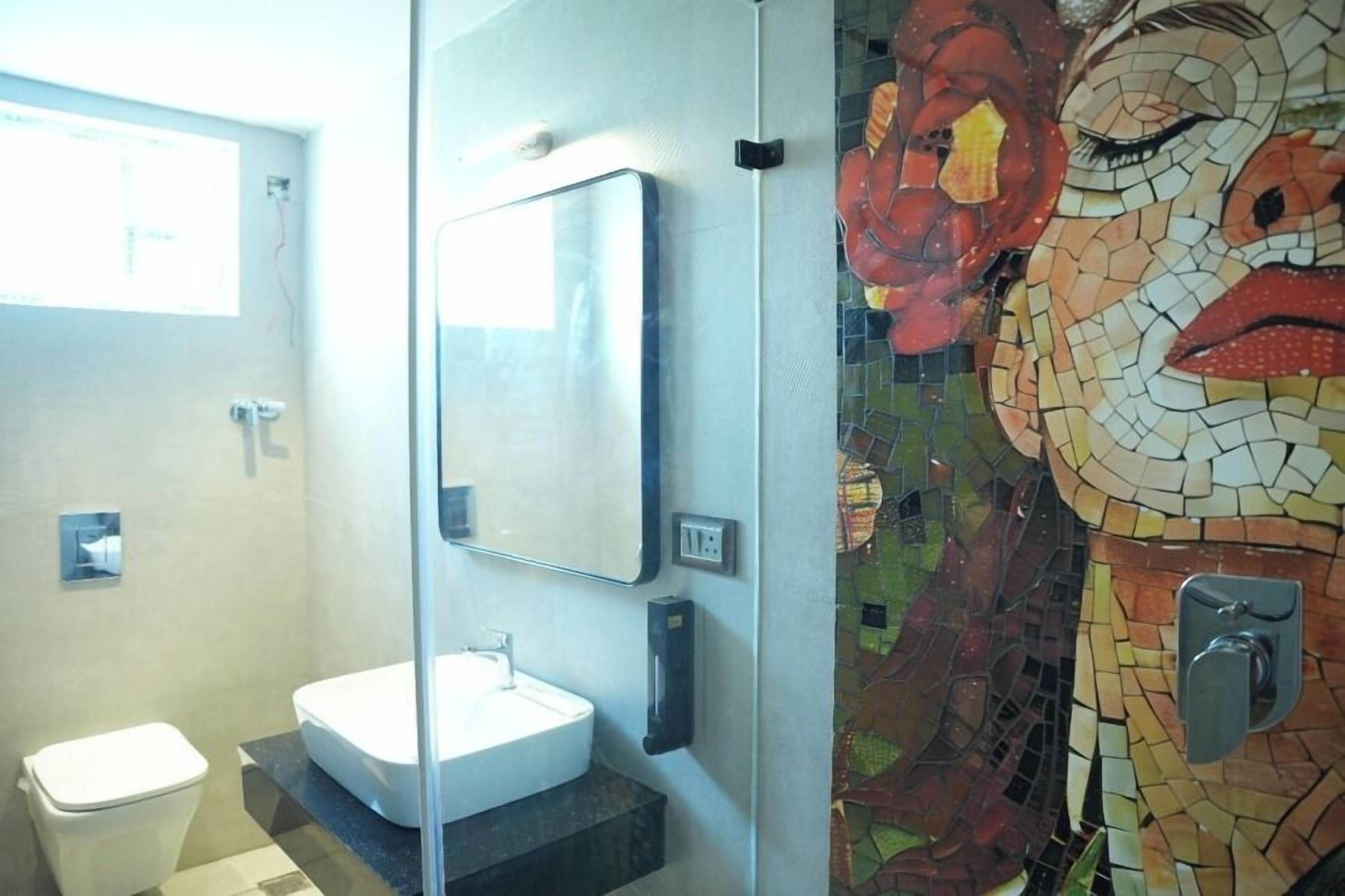 Ein Badezimmer mit Waschbecken, Spiegel und einer Wand aus Mosaiken.