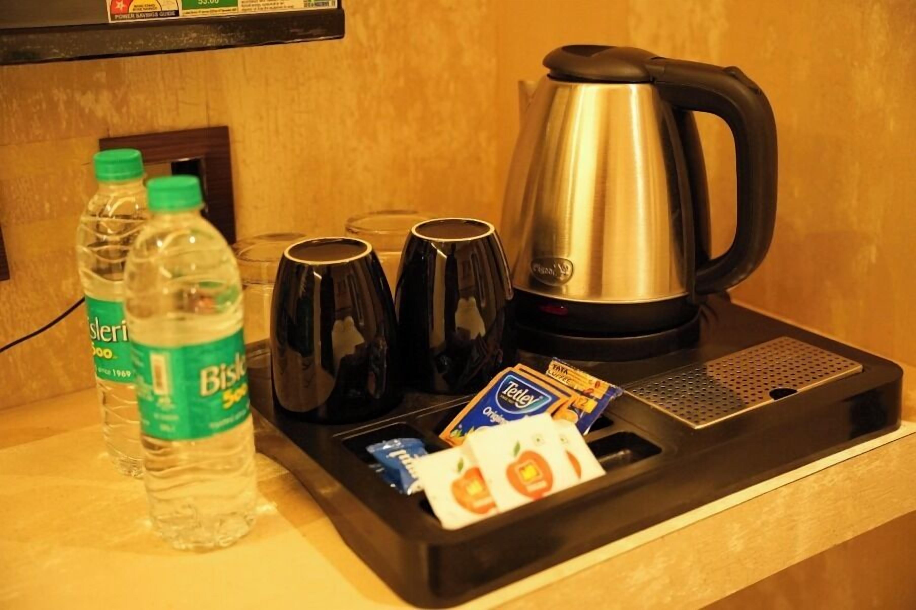 Dans une chambre d’hôtel, on trouve un mini-bar contenant une bouteille d’eau, deux verres, une cafetière et quelques en-cas.