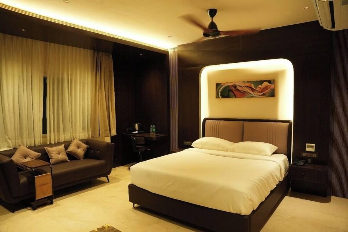 Een moderne hotelkamer met een groot bed, een slaapbank, een bureau en een plafondventilator.