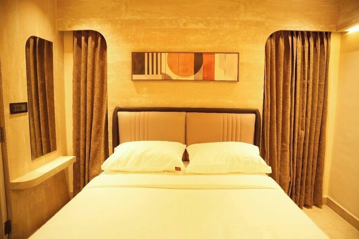 Een hotelkamer met een bed, gordijnen, een hoofdeinde en een kunstwerk aan de muur.