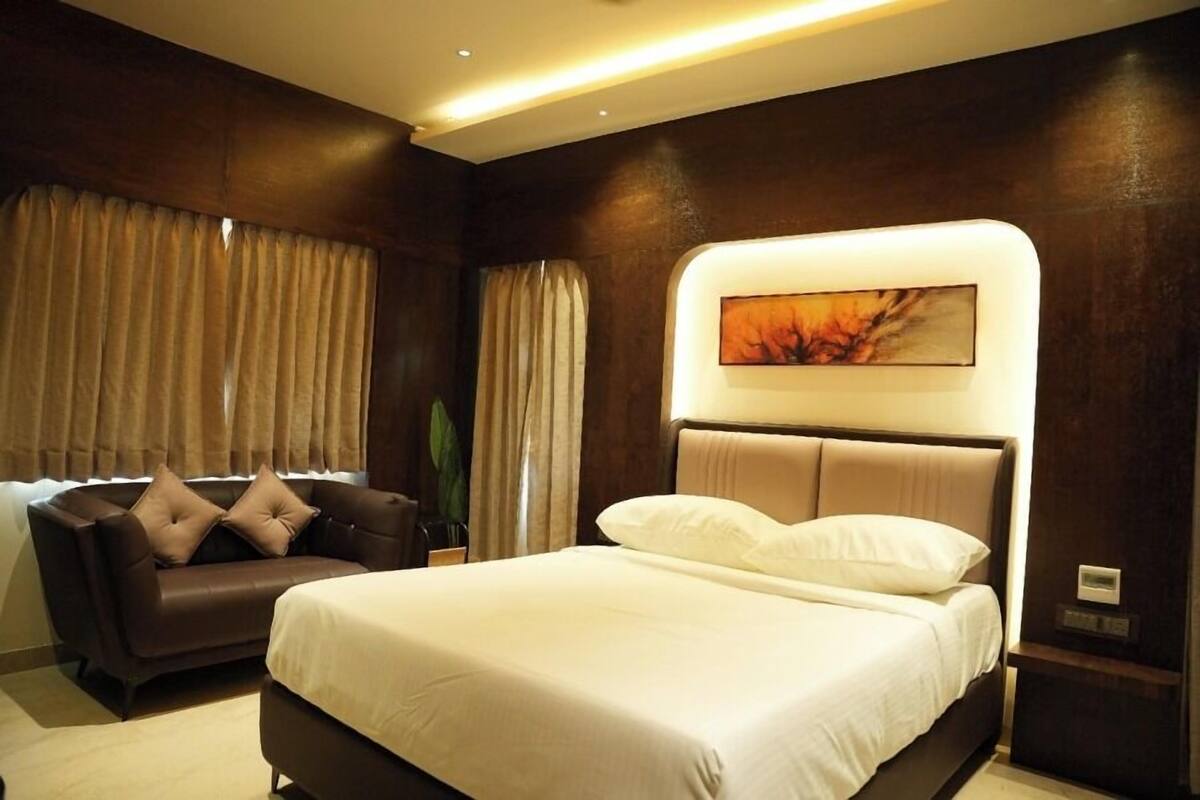 Een slaapkamer met een bed, een bank en een kunstwerk aan de muur.