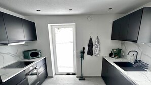 Eine moderne Küche mit dunklen Schränken, einer Mikrowelle, einem Spülbecken und einem Fenster.