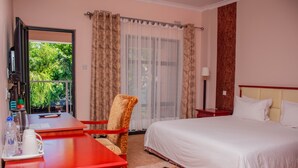 A hotel room with a bed, a desk with a chair, a TV, and a window with curtains. - Nalipiri eco resort  (Mulanje)