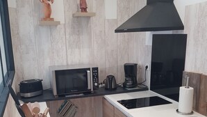 Una cocina compacta con microondas, cafetera y tostadora.