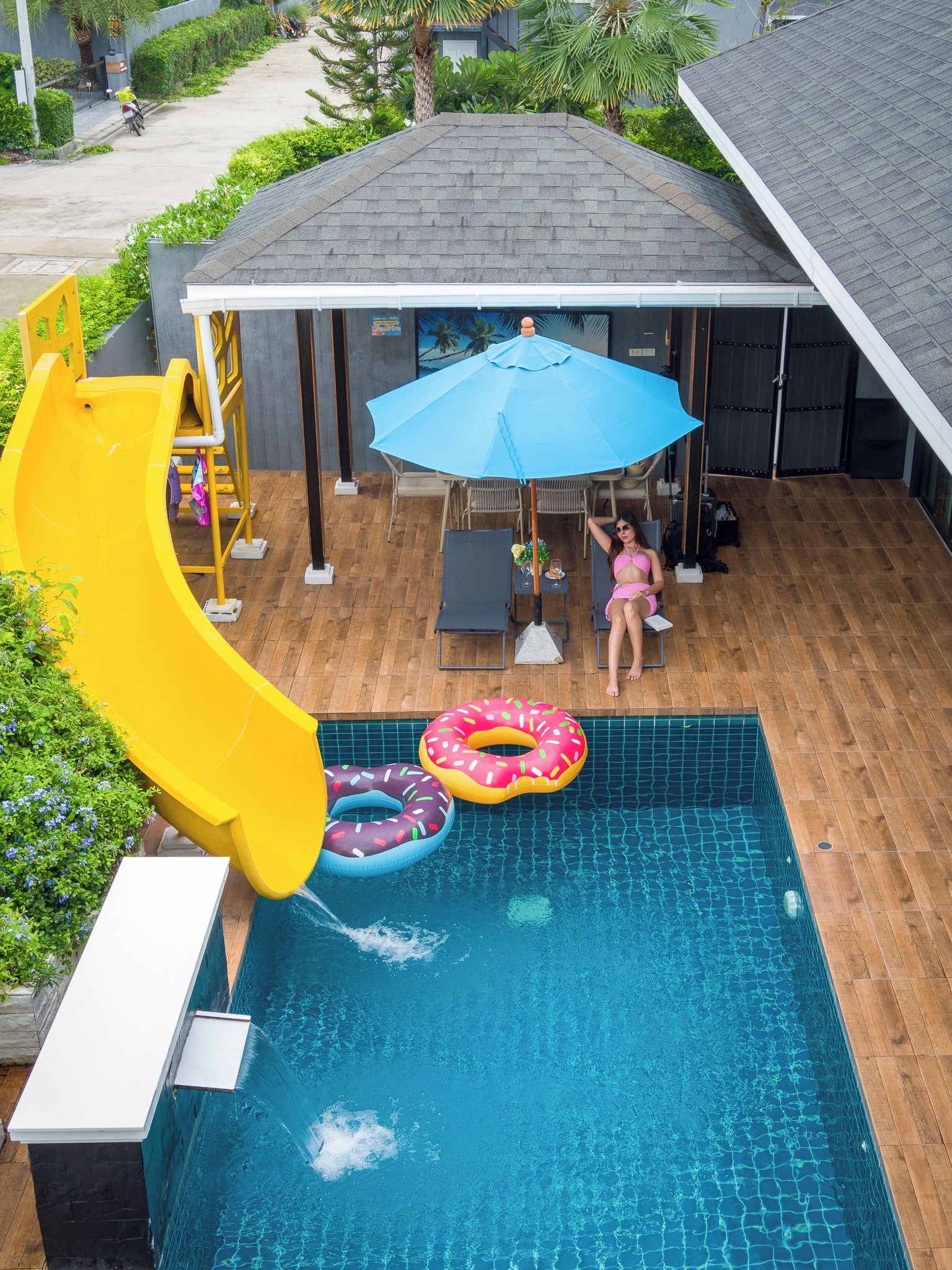 A swimming pool with a slide, lounge chairs, and a covered patio area.