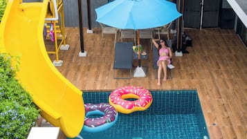 A swimming pool with a slide, lounge chairs, and a covered patio area.