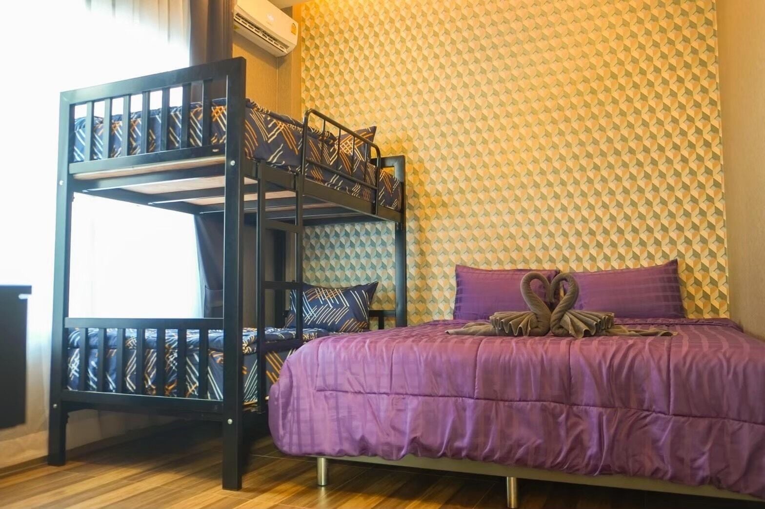 Una cama litera con un edredón púrpura y un papel tapiz de diseño geométrico.