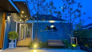 Ein modernes Gebäude mit Poolbereich, einer Bank und einem Schild mit der Aufschrift 'TRIPPLE B POOLVILLA, THAILAND'.