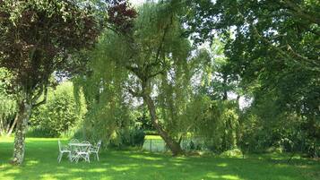 Un parc avec des arbres, une pelouse et une table en métal avec des chaises.