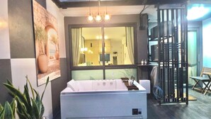 Una habitación moderna con un ventanal grande, un sofá, una mesita y una planta decorativa.